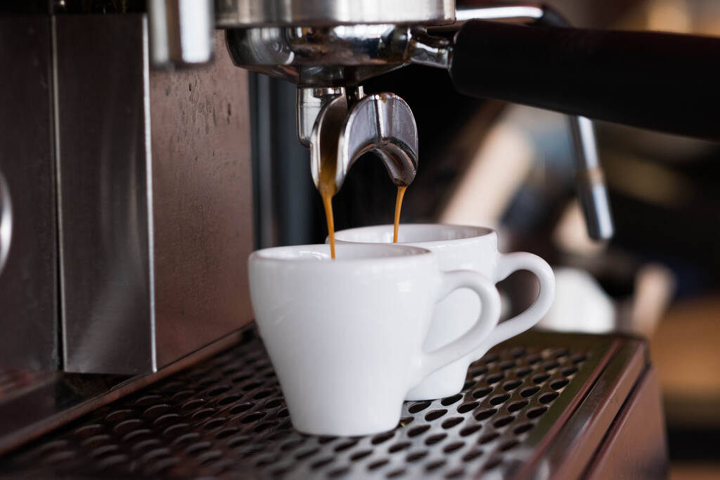 A kávéfőző két kávét tölt fehér csészébe.. - Fotó, kép