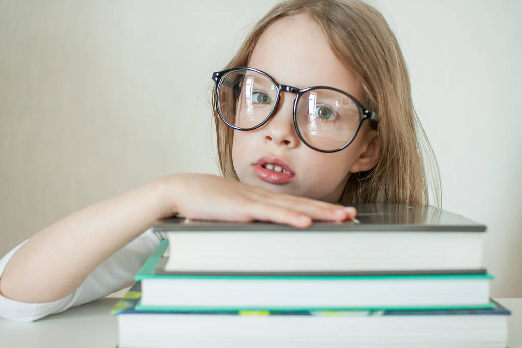 Gözlüklü küçük kız ev ödevi yapıyor, kitap okuyor.. - Fotoğraf, Görsel