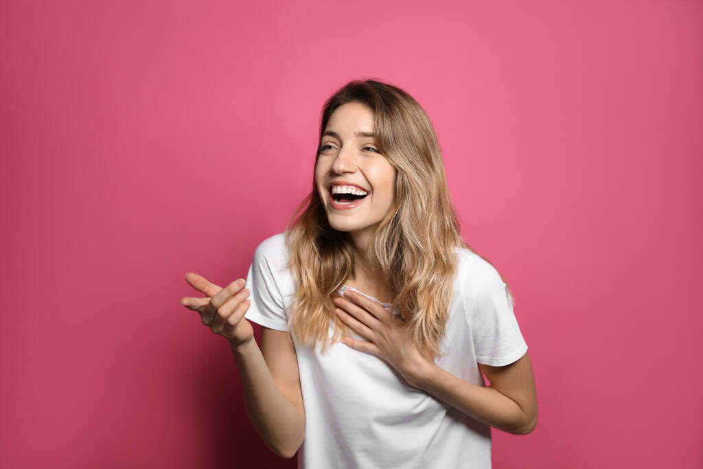 Vrolijke jonge vrouw lachen op roze achtergrond - Foto, afbeelding