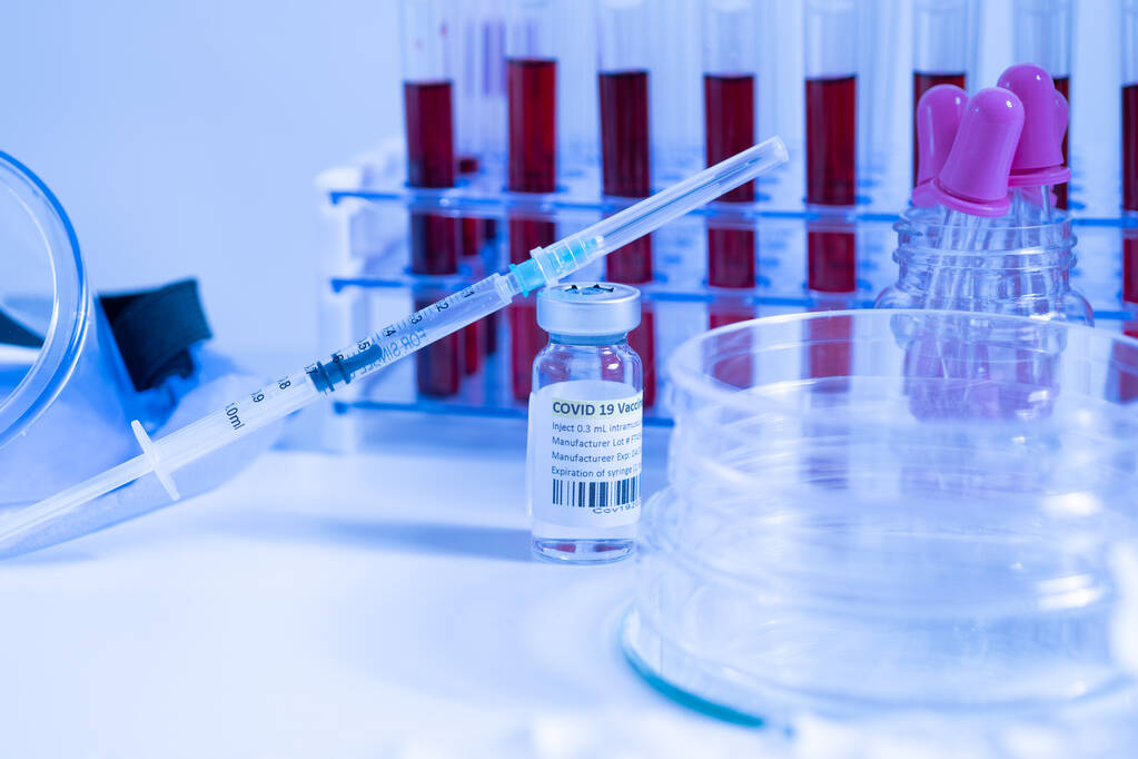 Скляний пляшковий флакон та шприц з вакциною проти коронавірусу Covid-19 у лабораторії науково-дослідного медичного закладу. Ампули з ліками на лабораторному столі медичного працівника. Концепція пандемії Сарс-Москва-2
.  - Фото, зображення