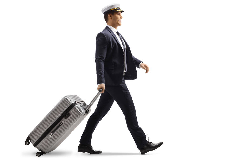 Full length profile shot of a young pilot walking with a suitcase isolated on white background - Photo, Image
