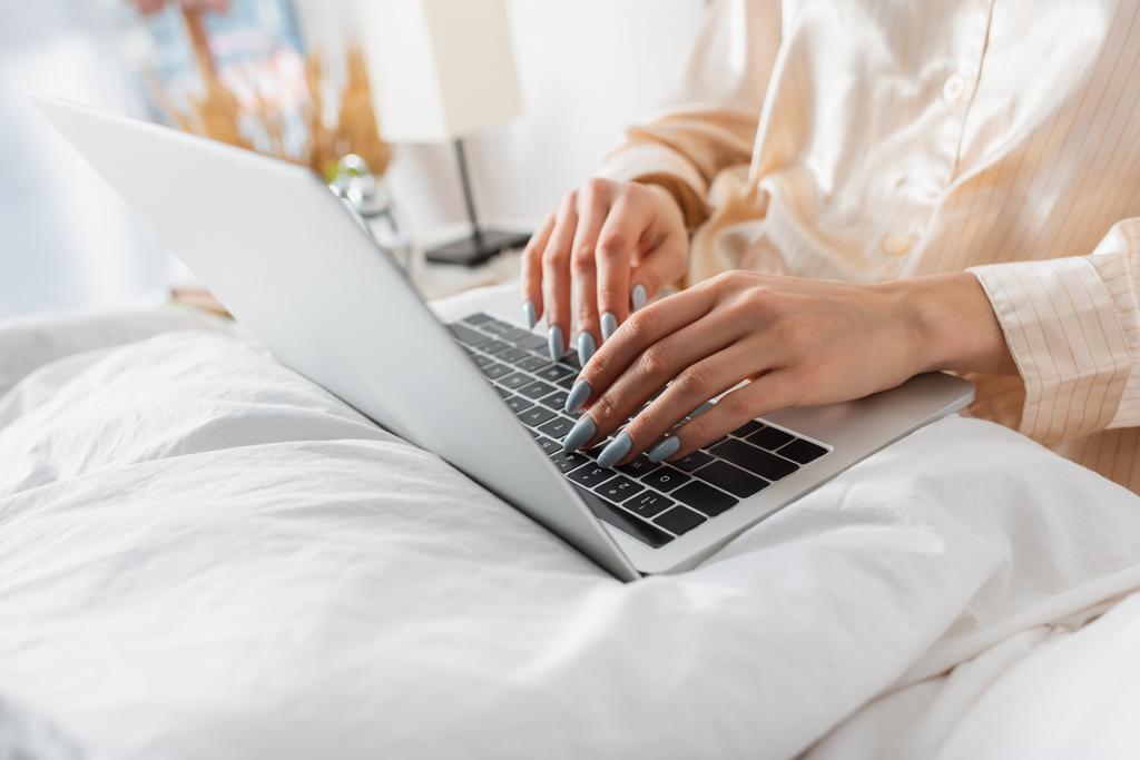 Gewassen weergave van de vrouw in pyjama met behulp van laptop op deken  - Foto, afbeelding
