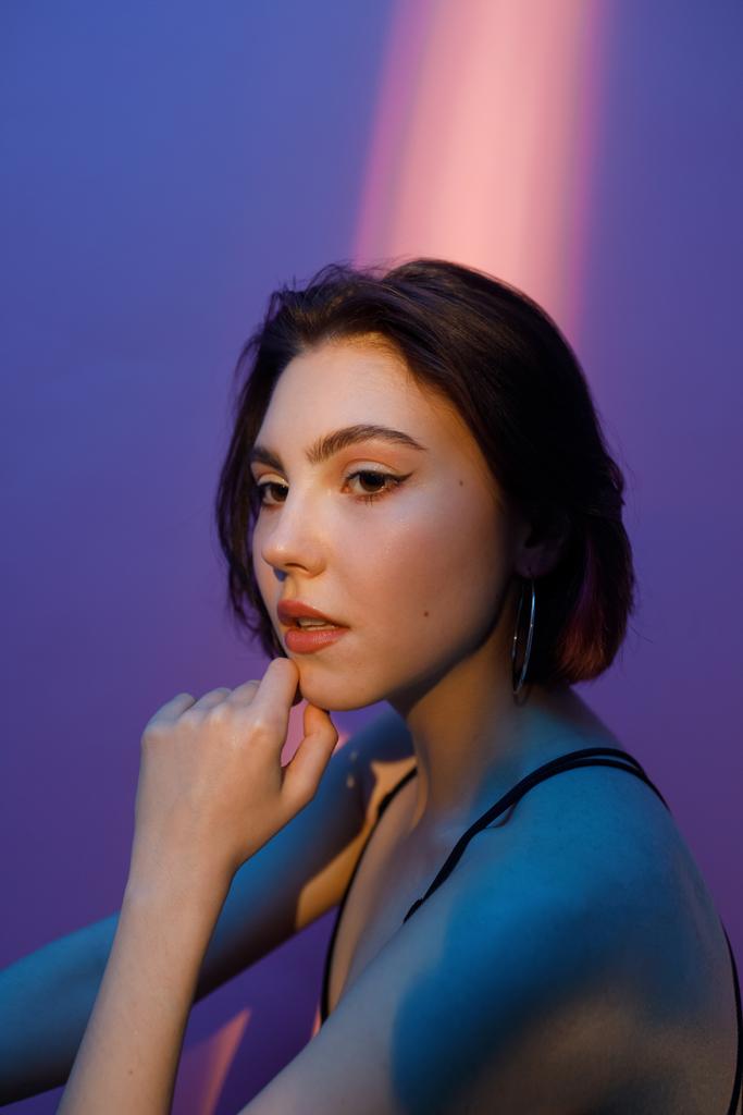 Porträt einer nachdenklichen jungen Frau auf violett und rosa Hintergrund - Foto, Bild