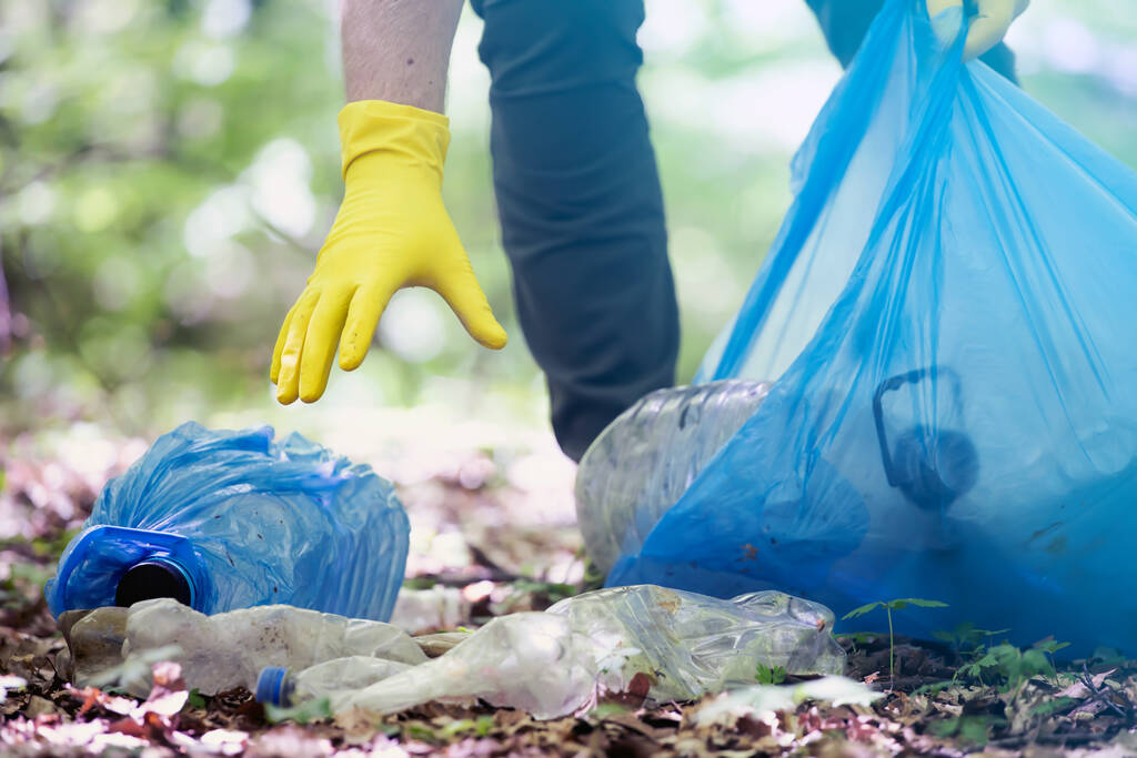 Ręczne zbieranie plastiku śmieci do czyszczenia lasów lub parków. Ochrona środowiska, Dzień Ziemi, koncepcja wolontariatu. - Zdjęcie, obraz