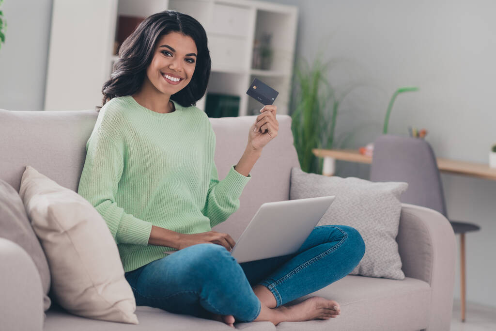 Pleine longueur profil côté photo de la jeune femme noire heureux sourire positif utiliser ordinateur portable tenir carte de crédit shopper acheter à l'intérieur - Photo, image