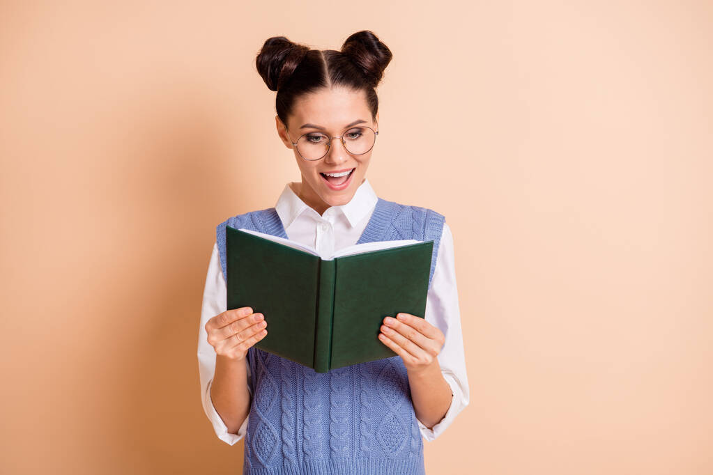 Foto di lucido impressionato giovane signora indossare occhiali giubbotto blu lettura libro aperto isolato colore beige sfondo - Foto, immagini