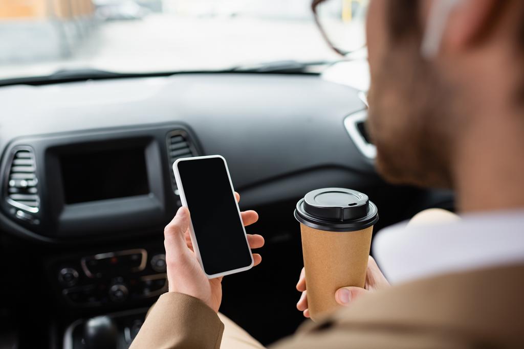 cropped view of blurred man in glasses holding smartphone with blank screen and paper cup in car  - Zdjęcie, obraz