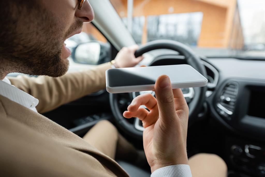 cropped view of bearded man recording voice message smartphone while driving car - Foto, afbeelding