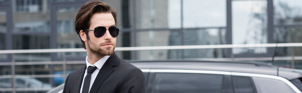 homme d'affaires en costume et lunettes de soleil près de la voiture moderne, bannière - Photo, image