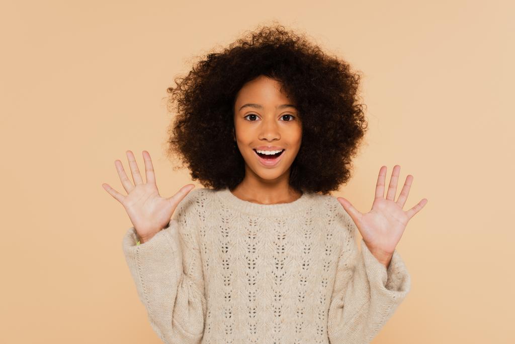 збуджена афроамериканська дівчина-підліток з руками, що показує долоні ізольовані на бежевому
 - Фото, зображення