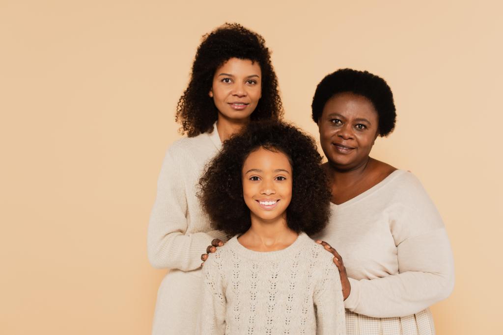 glimlachende familie van Afrikaanse Amerikaanse moeder, grootmoeder en kleindochter geïsoleerd op beige - Foto, afbeelding