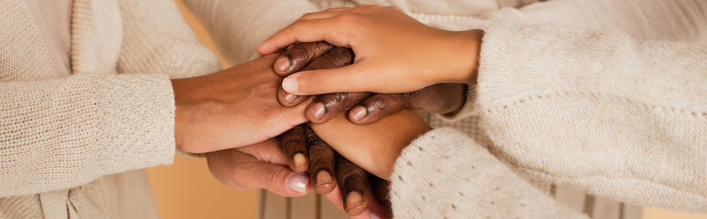 Afro-Amerikan orta yaşlı, yetişkin ve genç kadınların bej arka planda el ele tutuşmalarının yakın çekimleri. - Fotoğraf, Görsel