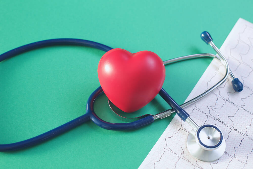Estetoscopio cardiográfico y corazón sobre fondo verde - Foto, Imagen