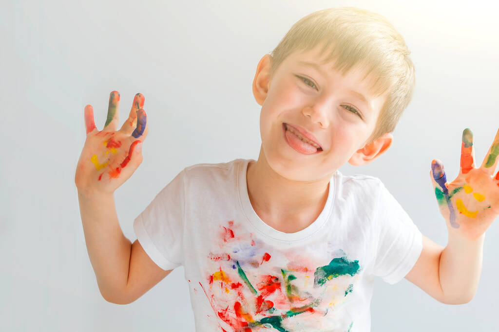 カラフルな塗装の手で楽しいかわいい未就学児の男の子5-6年の肖像画。笑顔の手だ。指描き、教育と子供の発達。幸せな子供時代 - 写真・画像