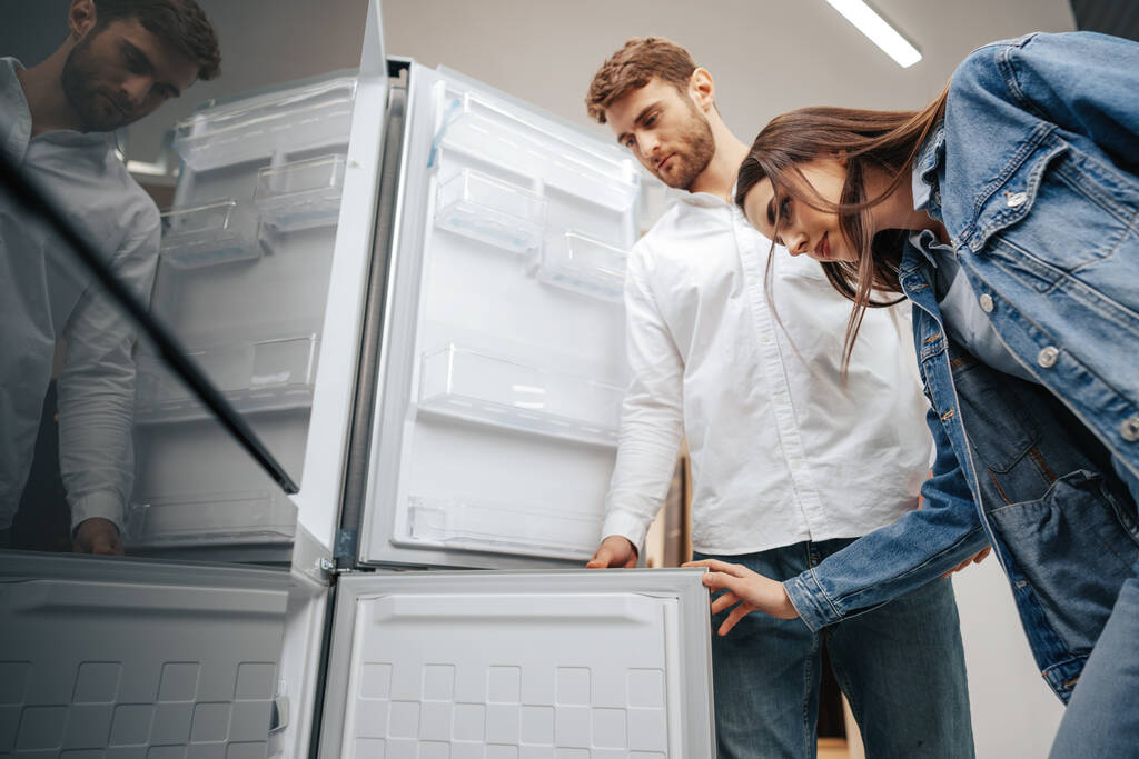 Молода пара вибирає новий холодильник в магазині побутової техніки
 - Фото, зображення
