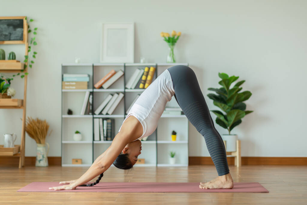 Calm of Beautiful Attractive Asian woman practice yoga Downward Facing dog or yoga Adho Mukha Svanasana pose to meditation with yoga in bedroom,Recreation in holidays concept - Photo, Image