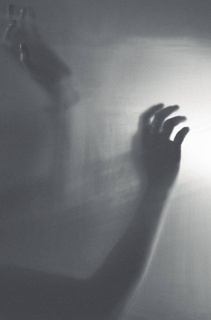 Aus dem Fokus ist eine weibliche Hand hinter einer Wand aus Milchfilm - Foto, Bild