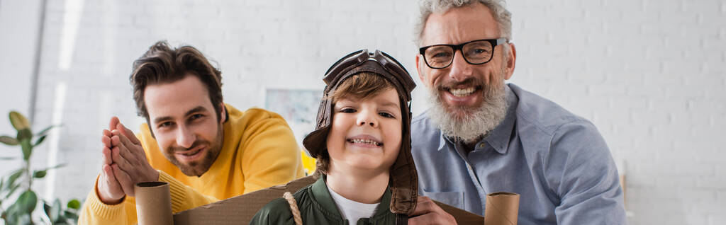 Χαμογελαστό αγόρι με στολή πιλότου που στέκεται δίπλα στους γονείς, πανό  - Φωτογραφία, εικόνα