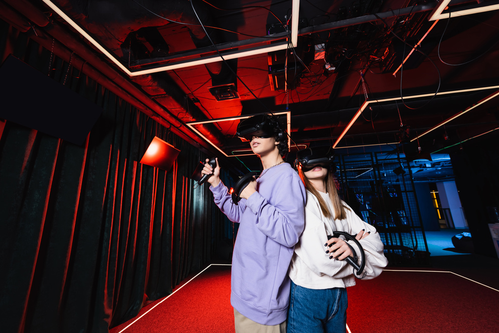 teenage gamers in vr headsets standing back to back in play zone - Photo, Image
