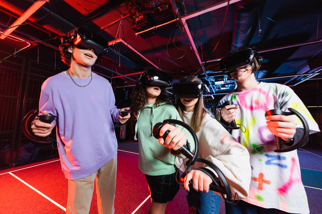 vrolijk interraciale tieners gaming in virtual reality headsets - Foto, afbeelding