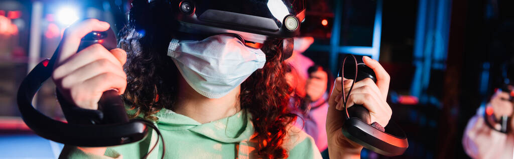 VR oyun sahasında tıbbi maske takan Afro-Amerikan kız manzarası. - Fotoğraf, Görsel