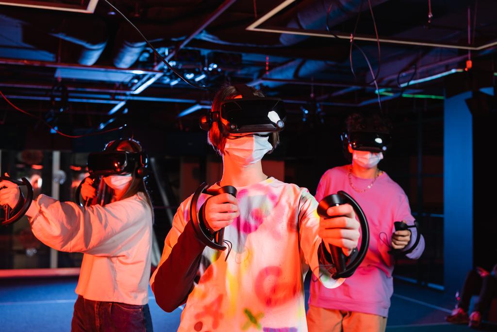 tiener vrienden gaming in vr headsets en medische maskers - Foto, afbeelding