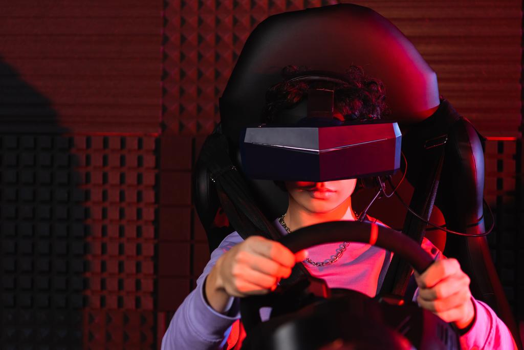 tiener jongen in virtual reality headset racen op auto simulator - Foto, afbeelding
