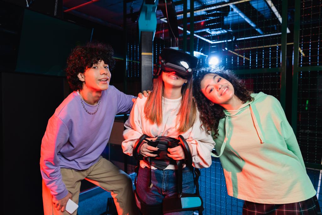 VR oyun sahasında kameraya gülümseyen neşeli çoklu etnik arkadaşlar - Fotoğraf, Görsel