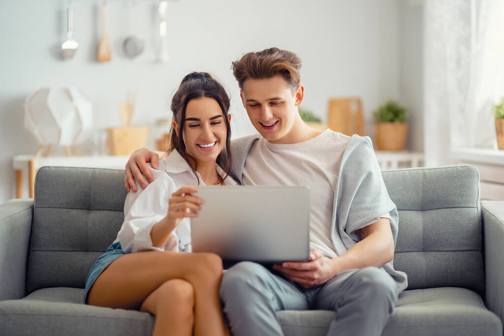 Le jeune couple utilise un ordinateur portable. Femme et homme s'amusent à rester à la maison. - Photo, image