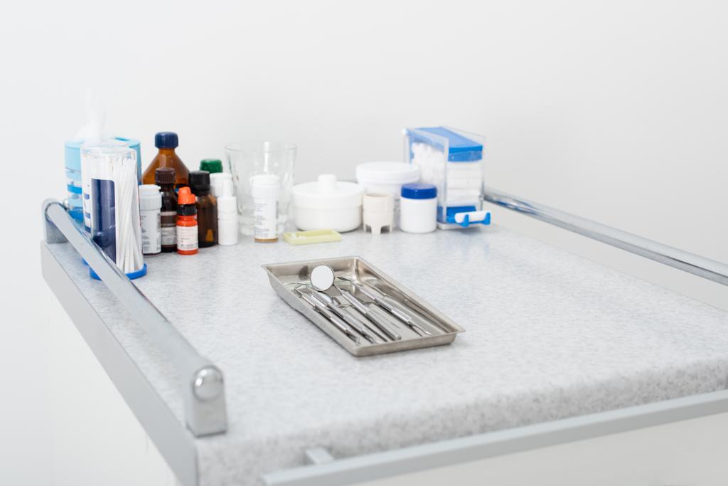 φάρμακα και καθαρά οδοντιατρικά εργαλεία σε δίσκο σε ιατρικό τραπέζι - Φωτογραφία, εικόνα