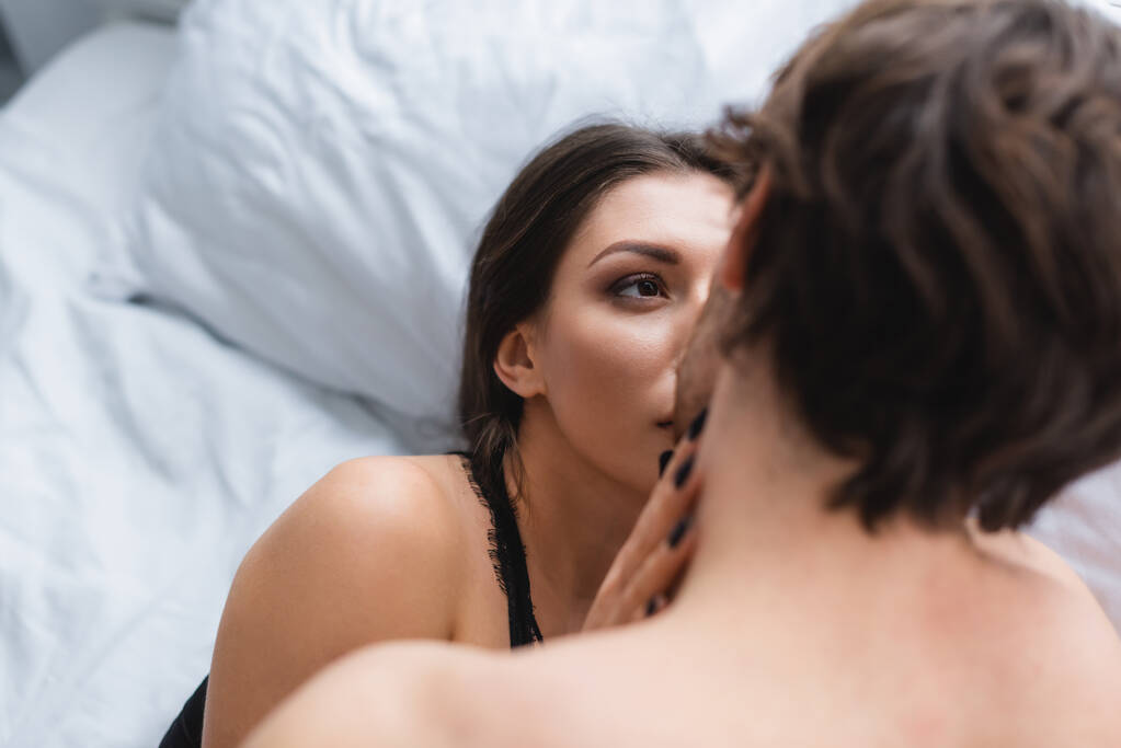Jovem mulher beijando namorado borrado na cama  - Foto, Imagem