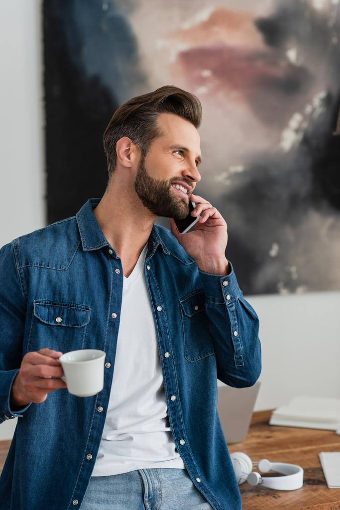 幸せなテレワーカーが携帯電話で話しながらコーヒーを飲みながら - 写真・画像