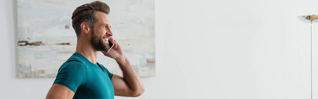 widok z boku uśmiechnięty człowiek rozmawiający przez telefon komórkowy w domu, baner - Zdjęcie, obraz