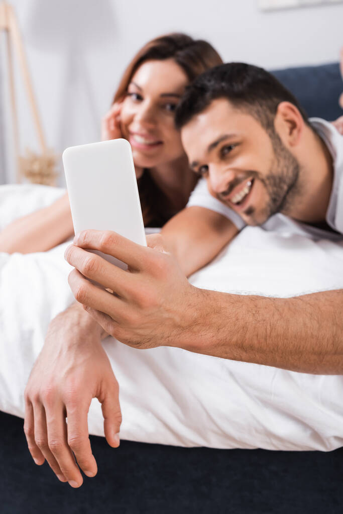 niewyraźne para biorąc selfie na smartfon na łóżko - Zdjęcie, obraz
