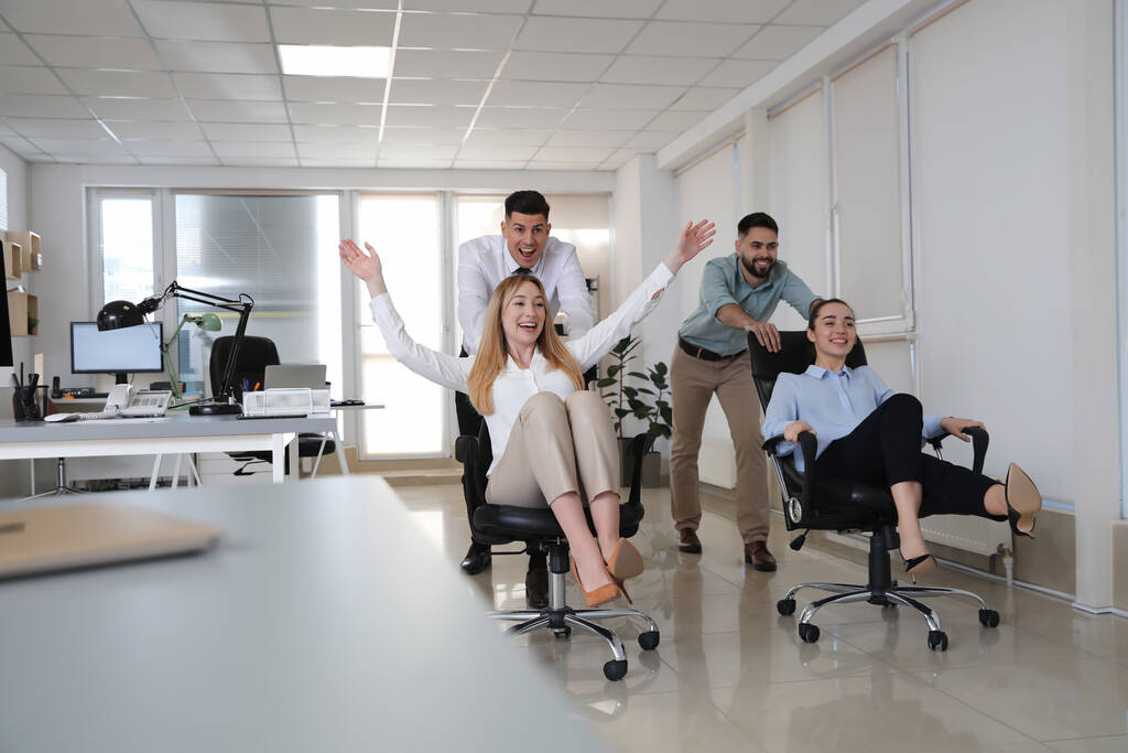 Happy pracowników biurowych jazda krzesła w miejscu pracy - Zdjęcie, obraz