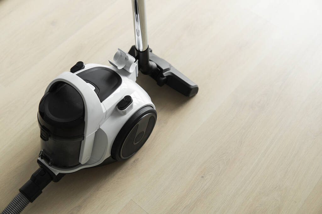 Bagless cyclone vacuum cleaner on a laminate. Electrical apparatus that by means of suction collects dust and small particles from floors and other surfaces. - Photo, Image