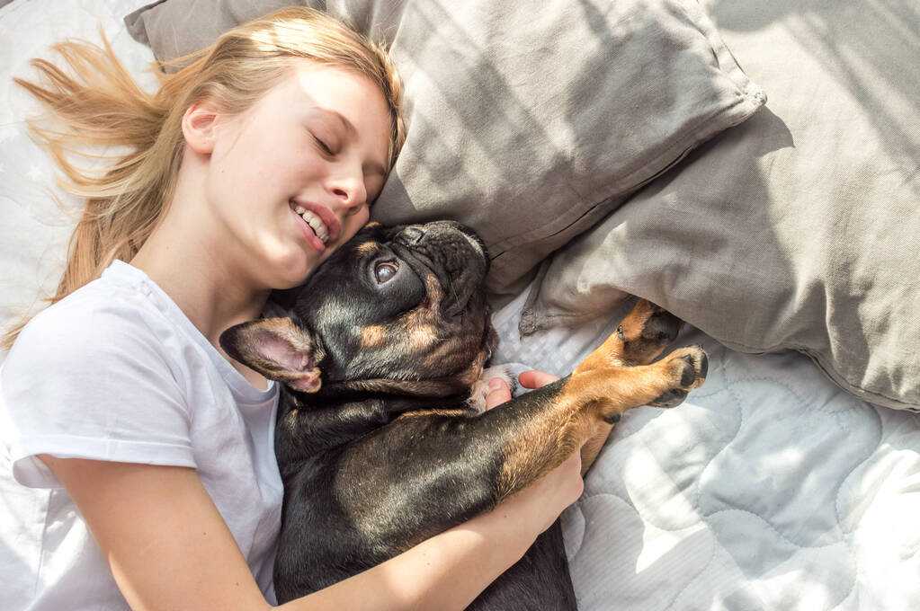 Власник обіймає свого собаку порода Французького бульдога на ліжку - Фото, зображення