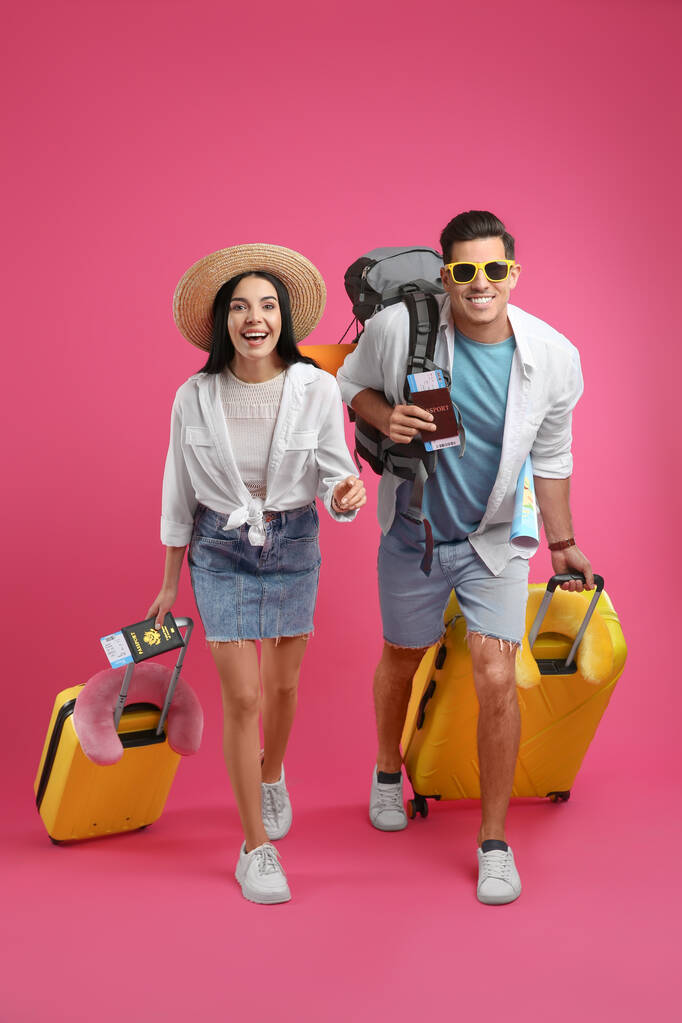 Touristenpaar mit Tickets, Pässen und Koffern auf rosa Hintergrund - Foto, Bild