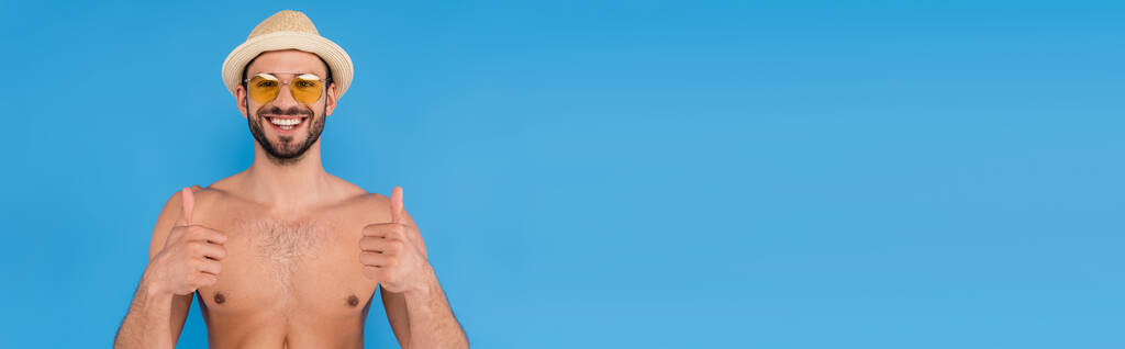 Uomo senza camicia con gli occhiali da sole che mostra i pollici in alto isolato su blu, banner   - Foto, immagini
