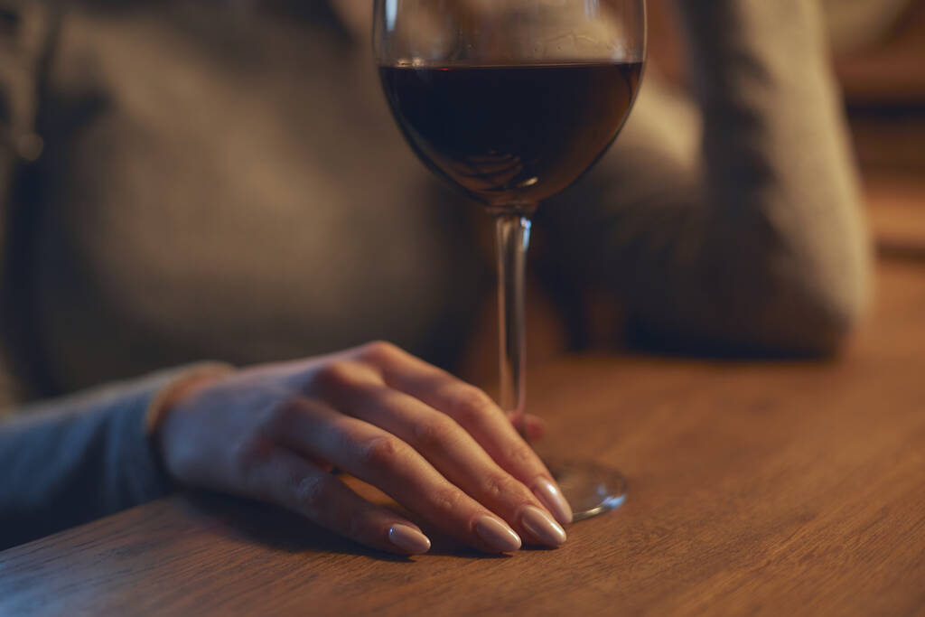 Χέρι ενός νεαρού όμορφου κοριτσιού που κρατά ένα ποτήρι κρασί σε εσωτερικό χώρο από ένα κομψό εστιατόριο κρασιού - Φωτογραφία, εικόνα