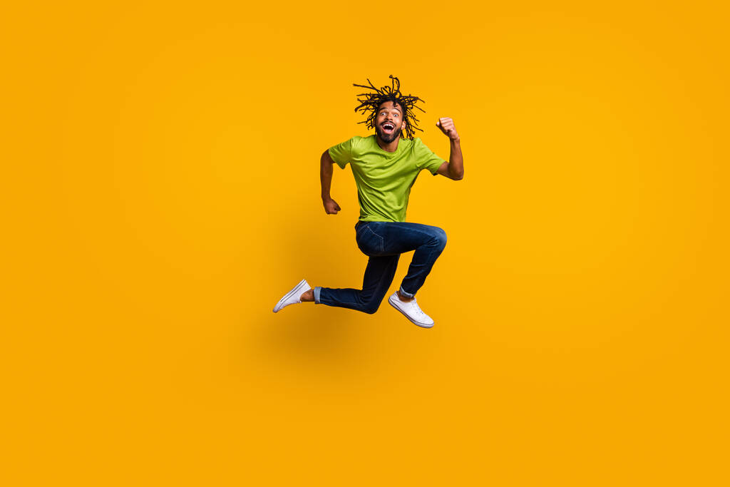 Foto portret full body view van grappige running guy springen omhoog geïsoleerd op levendige geel gekleurde achtergrond - Foto, afbeelding