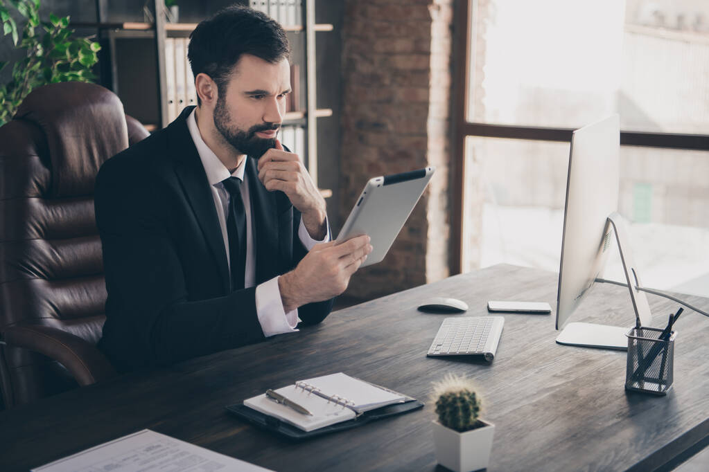 Foto di smart manager sit desk hold tablet dito mento leggere rapporto indossare cravatta camicia vestito in ufficio moderno all'interno - Foto, immagini