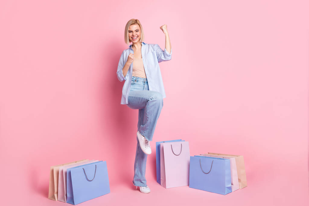 Lunghezza completa foto di allegra giovane donna positiva sollevare pugni vincitore vendita borse sconto isolato su sfondo di colore rosa - Foto, immagini