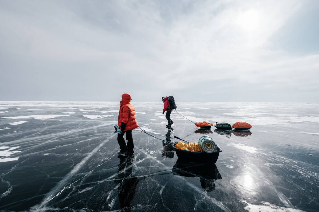 Пара туристов, идущих с санями по замерзшему льду озера Байкал. Зимние походы - Фото, изображение