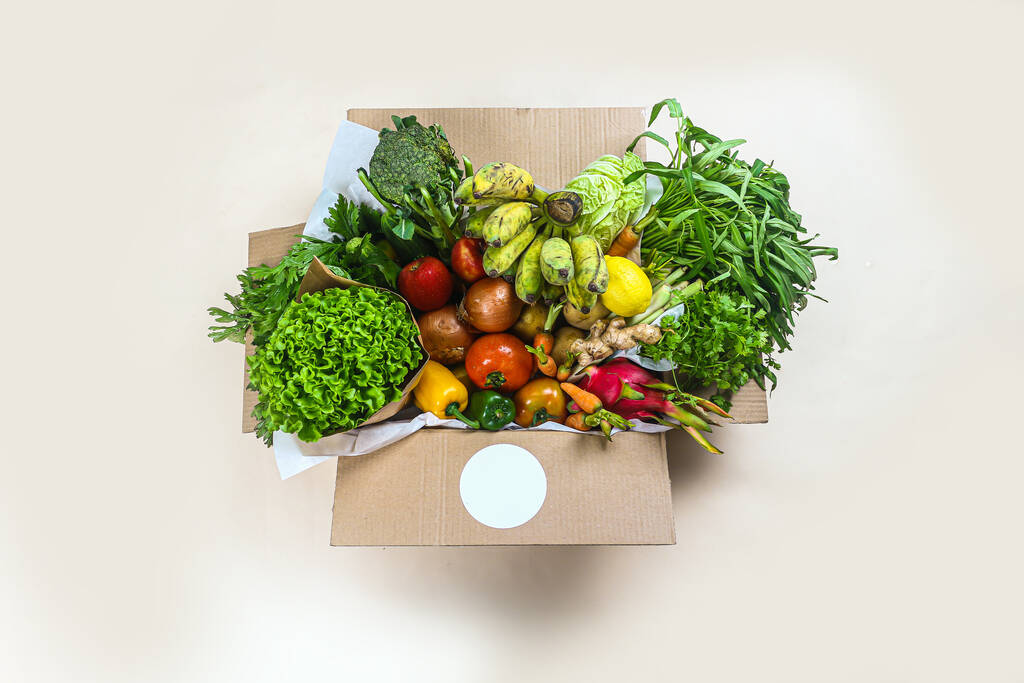 Крупный план свежих овощей в картонной коробке на столе доставлены на дом, коробка пожертвования с поставками продовольствия для людей, овощей и фруктов в картонной коробке. Селективный фокус. - Фото, изображение