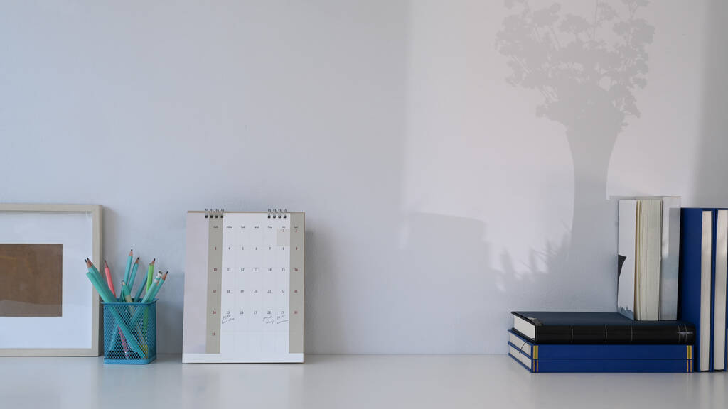 Κομψός χώρος εργασίας με ημερολόγιο, βιβλία, γραφική ύλη και χώρο αντιγραφής σε λευκό τραπέζι. - Φωτογραφία, εικόνα