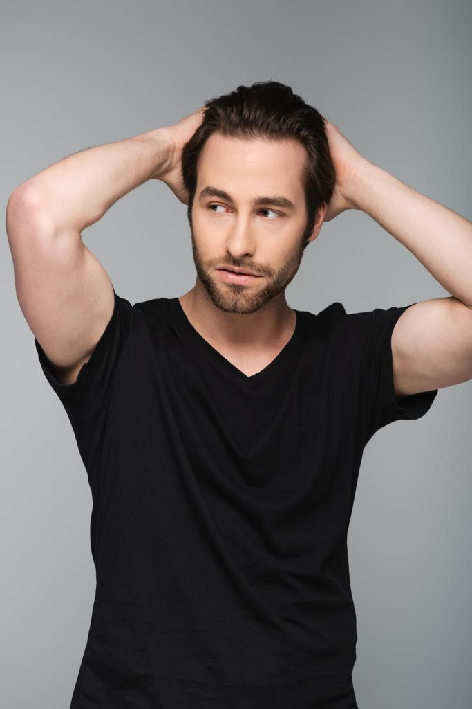 young bearded man in black t-shirt looking away and posing isolated on gray - Photo, Image