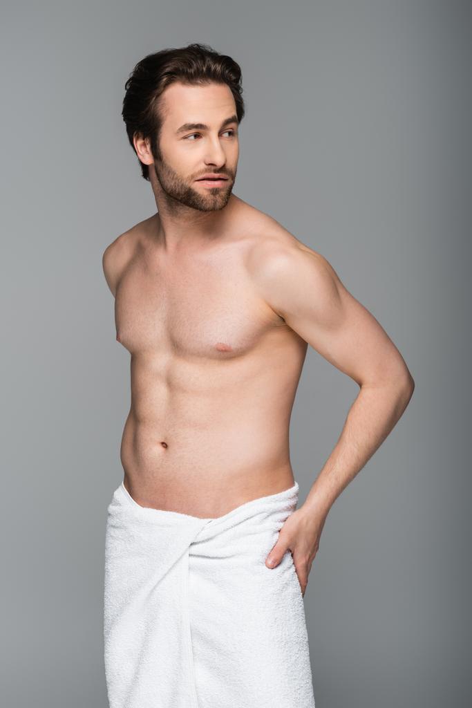 young muscular man wrapped in white towel looking away isolated on grey - Photo, Image
