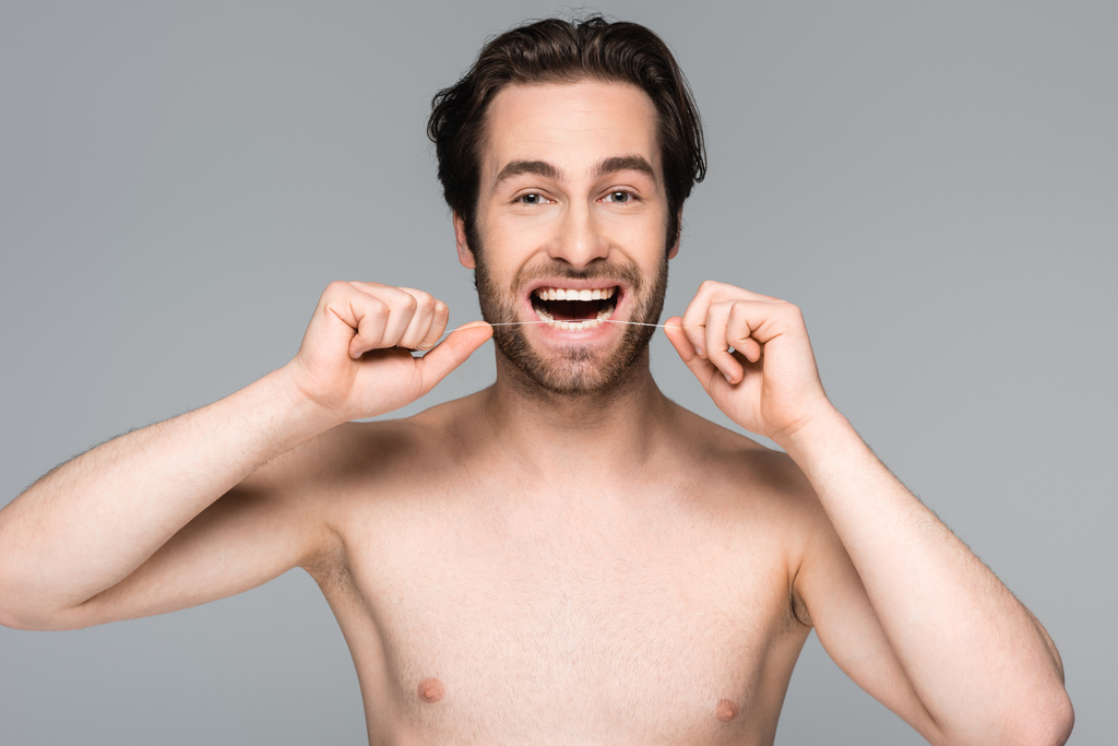 homme heureux et torse nu soie dentaire dents isolées sur gris - Photo, image