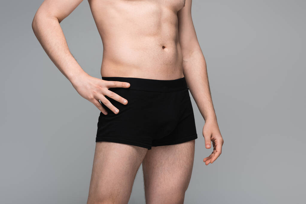 κομμένη άποψη του γυμνόστηθη άνθρωπος με μαύρα εσώρουχα θέτουν απομονωμένα σε γκρι - Φωτογραφία, εικόνα
